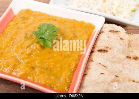 Tarka Dal - indische gelbe Knallerbse Curry mit Koriander garniert und serviert mit Pilau Reis und Chapati. Stockfoto