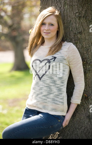 Hübsche blonde Frau an einen Baum gelehnt. Stockfoto