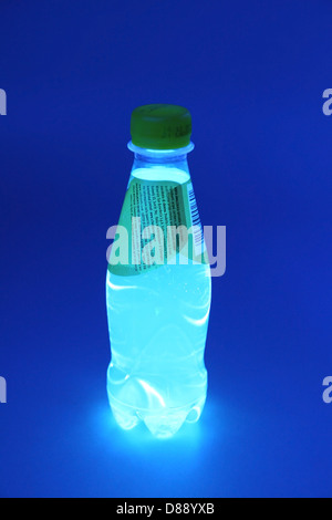 Kleines unbranded Tonikum Wasserflasche unter UV UV-Licht. Die Flasche ist glühend wie Chinin Inhalt im Tonic-Water fluoreszieren Stockfoto