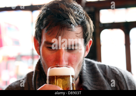 Ein Mann nimmt einen Schluck aus ein frisch gezapftes Bier in einem englischen Pub. Der schwarze Löwe, Kilburn Stockfoto