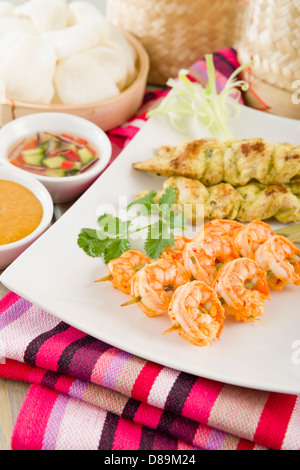 Sate Gai & Sate Goong - Thai Huhn und Garnelen Satays mit Gurke und Zwiebel-Relish und Erdnuss-Sauce serviert. Stockfoto