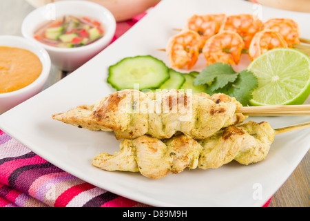 Sate Gai & Sate Goong - Thai Huhn und Garnelen Satays mit Gurke und Zwiebel-Relish und Erdnuss-Sauce serviert. Stockfoto