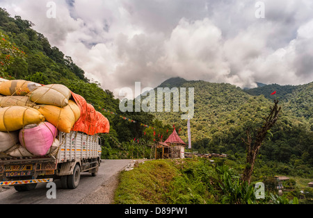 Überladene Lkw macht die beschwerliche Reise von Assam Tawang entlang der Hauptstraße mit Bergen und bewaldeten Hängen. Stockfoto