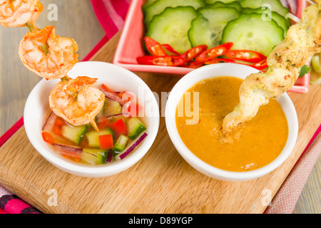 Sate Gai & Sate Goong - Thai Huhn und Garnelen Satays mit Gurke und Zwiebel-Relish und Erdnuss-Sauce serviert. Stockfoto