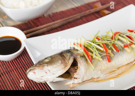 Gedünsteter Fisch - chinesischen Stil gedünstet Seebarsch mit Ingwer, Chili und Frühlingszwiebeln garniert. Stockfoto