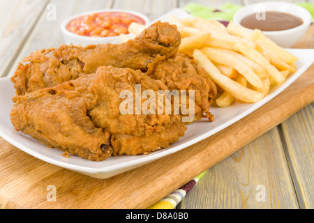 Fried Chicken & Chips - Hähnchenteile auf den Knochen in würziger Mehl überzogen und frittiert. Pommes frites, Bohnen und Soße Seiten. Stockfoto