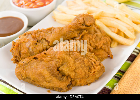 Fried Chicken & Chips - Hähnchenteile auf den Knochen in würziger Mehl überzogen und frittiert. Pommes frites, Bohnen und Soße Seiten. Stockfoto