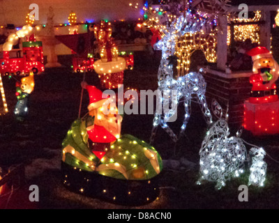 Weihnachtslichter und festliche Rasendekorationen im Vorgarten sorgen für eine lebhafte und farbenfrohe Weihnachtsszene. Die Lichter beleuchten die Dekoration und verstärken die festliche Atmosphäre. Stockfoto