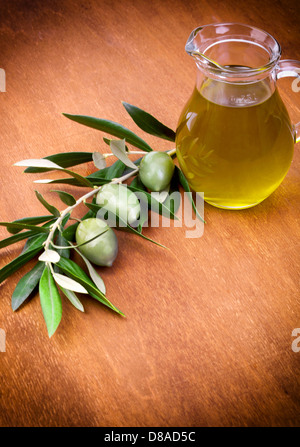 Oliven und eine Flasche Olivenöl isoliert auf Holztisch Stockfoto