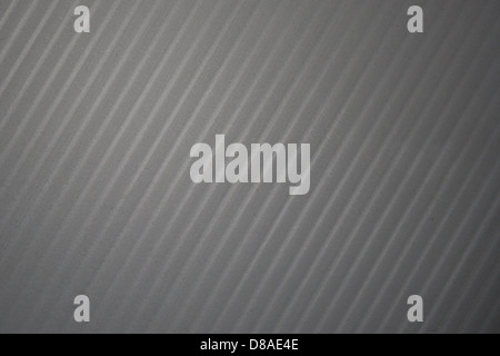 Nahaufnahme einer grauen Kunststoffoberfläche mit diagonalen Streifen. Die Textur zeichnet sich durch ein glattes, modernes Design aus, das häufig in industriellen oder kommerziellen Anwendungen aufgrund seiner Haltbarkeit und praktischen Eigenschaften verwendet wird. Stockfoto