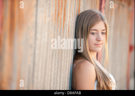 Eine junge Frau lehnt sich an eine alte rostigem Eisen-Wand nach unten weg von der Kamera Stockfoto