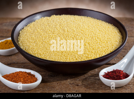 Rohen Couscous in einer Holzschale mit Gewürzen Stockfoto