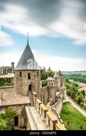 Malerische Aussicht auf alte Carcassonne-Schloss in Frankreich mit grauen Mauern und Türmen. Grün der Bäume und bewölktem Himmel im Hintergrund. Stockfoto