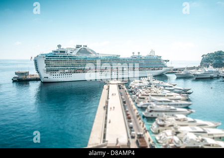 Großes Kreuzfahrtschiff im Hafen. Luxus-Liner im blauen Wasser unter klarer Himmel mit vielen Yachten am Liegeplatz im Vordergrund. Komfortable Stockfoto