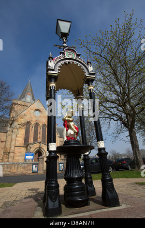 Stadt von Dornoch, Schottland. Die kunstvollen öffentlichen gut mit Dornoch Kathedrale im Hintergrund des späten 19. Jahrhunderts. Stockfoto