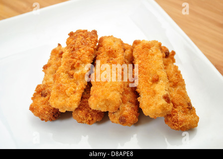 Sieben gebackene Fischstäbchen auf einem weißen Teller Stockfoto