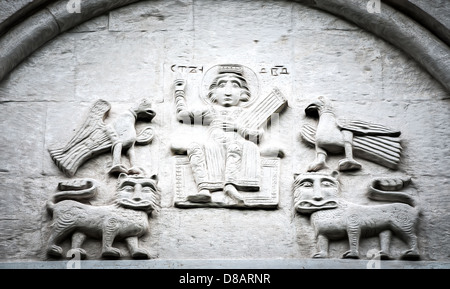 Große Wand in der Kirche fünf fiktive Charaktere zeigen. Zwei Vögel auf zwei Löwen, Mann in Mitte sitzt. Primitive Stein Stockfoto