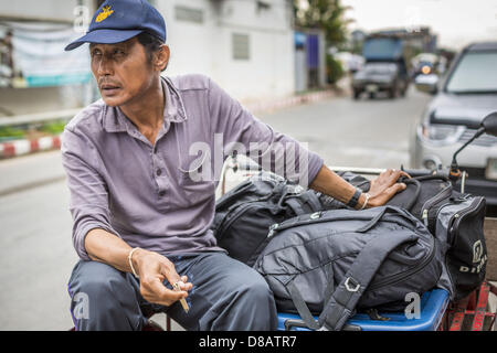 23. Mai 2013 - Mae Sot, Tak, Thailand - wartet birmanischer Mann Freundschaftsbrücke zwischen Mae Sot, Thailand und Myawaddy, Myanmar, für den Tag zu öffnen, so dass er nach Burma zurückgehen kann. Fünfzig Jahre der politischen Unruhen in Burma (Myanmar) hat Millionen von Burmesen ihr Land verlassen geführt. Viele haben im benachbarten Thailand niedergelassen. Mae Sot, an der Mae Nam Moie (Moie River) ist das Zentrum der birmanischen Exil lebende Gemeinschaft im zentralen Westen Thailands. Es gibt Hunderte von Tausenden von burmesischen Flüchtlingen und Migranten im Bereich. Viele Leben ein Schattendasein ohne Papiere und ohne Rückgriff, wenn sie übereinander Stockfoto