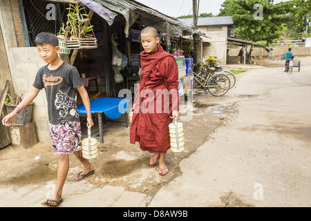 23. Mai 2013 - Mae Sot, Tak, Thailand - Burma Novize und seine Assistentin Spaziergang durch Mae Sot, runden Thailand auf seine Morgen Almosen. Fünfzig Jahre der politischen Unruhen in Burma (Myanmar) hat Millionen von Burmesen ihr Land verlassen geführt. Viele haben im benachbarten Thailand niedergelassen. Mae Sot, an der Mae Nam Moie (Moie River) ist das Zentrum der birmanischen Exil lebende Gemeinschaft im zentralen Westen Thailands. Es gibt Hunderte von Tausenden von burmesischen Flüchtlingen und Migranten im Bereich. Viele Leben ein Schattendasein ohne Papiere und ohne Rückgriff, wenn sie die thailändische Behörden überqueren. Die Burmesen haben thei Stockfoto