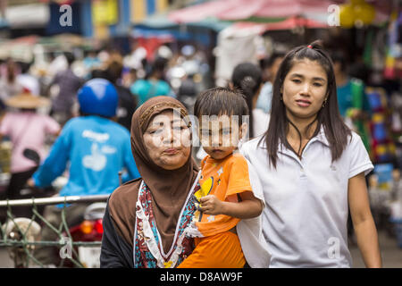 23. Mai 2013 - Mae Sot, Tak, Thailand - trägt birmanischen Muslima ihren Sohn durch den burmesischen Markt in Mae Sot, Thailand. Fünfzig Jahre der politischen Unruhen in Burma (Myanmar) hat Millionen von Burmesen ihr Land verlassen geführt. Viele haben im benachbarten Thailand niedergelassen. Mae Sot, an der Mae Nam Moie (Moie River) ist das Zentrum der birmanischen Exil lebende Gemeinschaft im zentralen Westen Thailands. Es gibt Hunderte von Tausenden von burmesischen Flüchtlingen und Migranten im Bereich. Viele Leben ein Schattendasein ohne Papiere und ohne Rückgriff, wenn sie die thailändische Behörden überqueren. Die Burmesen haben ihre eigenen schoo Stockfoto