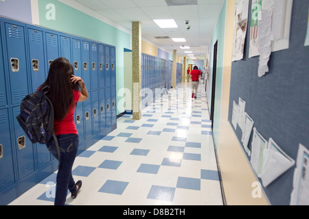 Weibliche High-School-Schüler, die das Tragen eines Rucksacks, Spaziergänge durch Flur mit Schließfächern in Austin, Texas-Schule Stockfoto