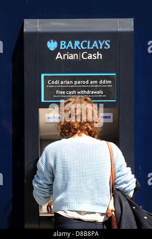 Eine Frau zieht sich Bargeld aus einem Barclays-Geldautomaten / atm. Stockfoto