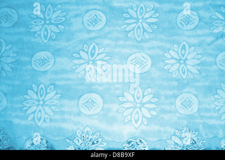 Eine Nahaufnahme aus blauem Stoff mit Blumen- und Kreismustern. Das Bild konzentriert sich auf die Textur des Textils und die komplizierten Designelemente und unterstreicht dessen visuelle Anziehungskraft. Stockfoto
