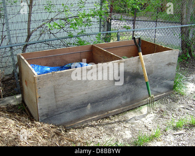 Eine Kompostkiste ist mit einer Heugabel dargestellt, die an sie geneigt ist. Der Abfalleimer ist mit organischen Abfällen wie Blättern, Lebensmittelresten und Pflanzenstoffen gefüllt, die sich zersetzen und nährstoffreichen Kompost für den Garten oder die Landwirtschaft erzeugen. Das Image betont nachhaltige Gartenarbeit und eine umweltfreundliche Abfallwirtschaft. Stockfoto
