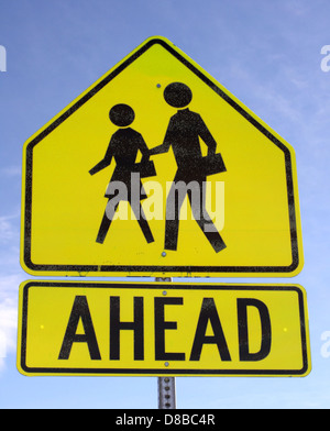 Dieses Stockfoto zeigt ein Standardkreuz vor dem Verkehrsschild. Das Schild wird verwendet, um die Fahrer über einen bevorstehenden Fußgängerübergang zu informieren und so die Straßenverkehrssicherheit und das Bewusstsein zu fördern. Die gelben und schwarzen Farben machen es für den Autofahrer gut sichtbar und deutlich. Stockfoto