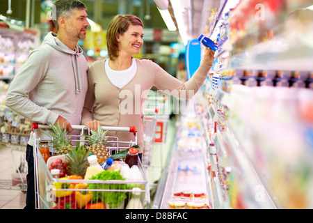 Bild des glücklichen Paares mit Cart Auswahl Produkte im Supermarkt Stockfoto
