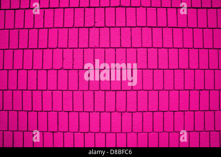 Eine Nahaufnahme einer pinkfarbenen Ziegelwand mit vertikaler Ausrichtung, die ein einzigartiges und auffälliges Design zeigt. Die lebendige Farbe verleiht dem traditionellen Backsteinmuster eine moderne, auffällige Ästhetik. Stockfoto