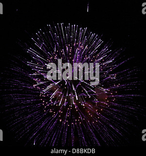 Ein leuchtendes violettes Feuerwerk, das am Nachthimmel platzt und Sternenmuster erzeugt. Die hellen Farben und die dramatische Beleuchtung sorgen für eine festliche Atmosphäre während einer Feier oder Veranstaltung. Stockfoto
