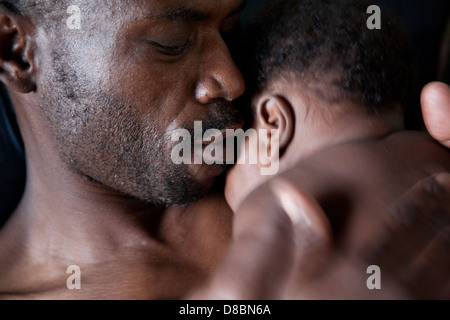 Porträt eines afrikanischen Vaters sein Kleinkind Baby Wange küssen. Stockfoto