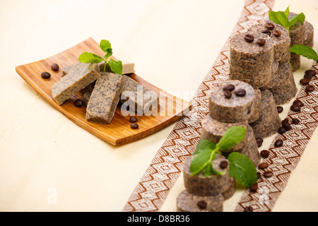 Haufen von handgemachte aromatisierte Seife Bars mit Kaffeebohnen und grünen Lavendel Blätter auf Holzständer. Stockfoto