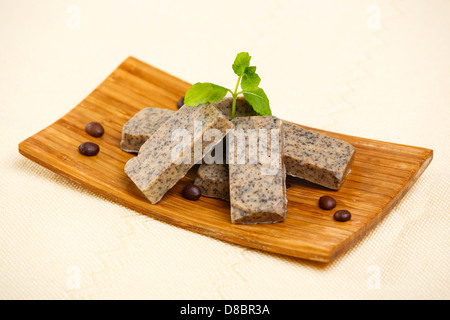 Haufen von handgemachte aromatisierte Seife Bars mit Kaffeebohnen und grünen Lavendel Blätter auf Holzständer. Stockfoto