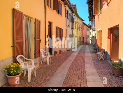 Schmale gepflasterte Straße unter bunten Wohnhäuser in der Stadt von Serralunga D'Alba in Piemont, Italien. Stockfoto