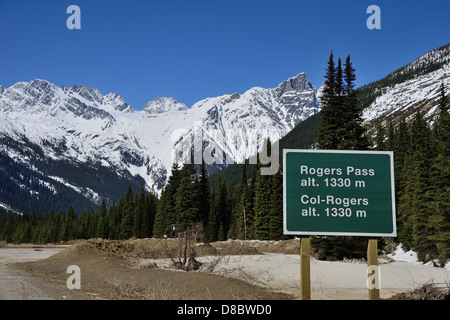 Schild am Rogers Pass im Glacier Nationalpark in den kanadischen Rockies mit schneebedeckten Berge in der Ferne Stockfoto