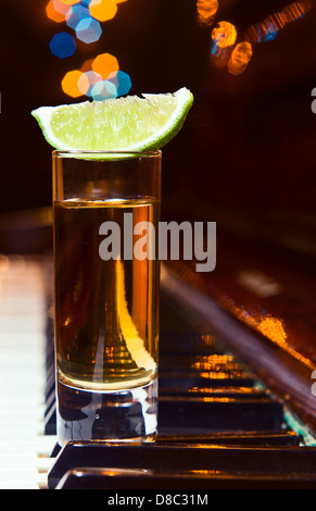 Glas mit Tequila auf ein altes Klavier Stockfoto