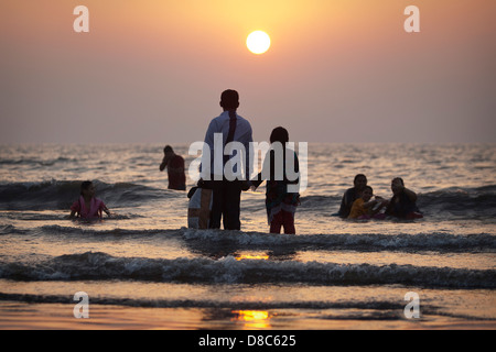 Menschen beobachten den Sonnenuntergang an einem Strand in Mumbai, Indien Stockfoto