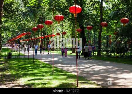 Menschen schlendern Sie entlang einem Pfad gesäumt mit Lampions in Łazienki Park Łazienkowski, der größten Grünanlage in Warschau. Stockfoto