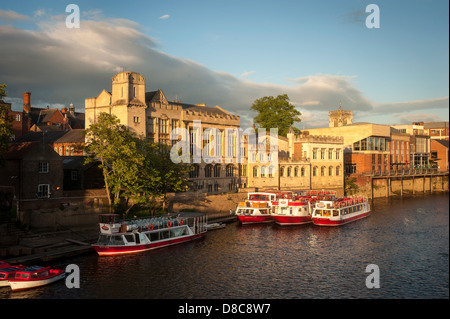 River Ouse mit einer Flotte von Kreuzfahrt- und Touristenausleihbooten, die an einem sonnigen Sommerabend in York an der Guildhall festgemacht wurden. Stockfoto