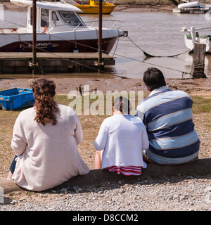 Eine Rückansicht von 3 großen Menschen essen Fisch und Chips am Hafen in Southwold, Suffolk, England, Großbritannien, Uk Stockfoto