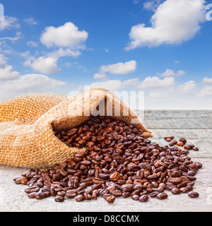 Kaffeebohnen verschütten vom Sack und blauer Himmel - frisch gebratenen Kaffeebohnen aus Sackleinen oder Jute meschotschek verschütten... Stockfoto
