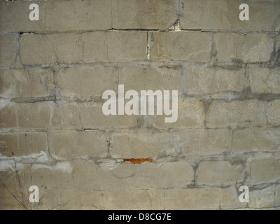 Dieses Bild zeigt eine strukturierte, verwitterte Ziegelwand mit einem veralteten Aussehen, die die natürlichen Farbvariationen und die abgenutzte Oberfläche zeigt, die typisch für alte Ziegelbauten ist. Stockfoto