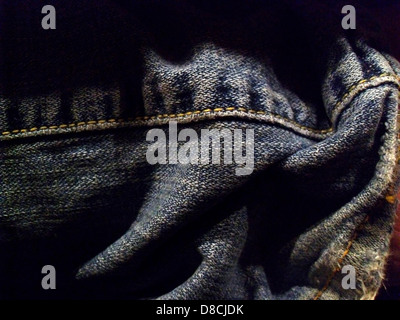 Gezeigt wird eine Jeans mit Falteneffekt und auffälligen Falten. Die Jeans hat eine klassische blaue Farbe und die Textur des Materials ist deutlich sichtbar. Stockfoto