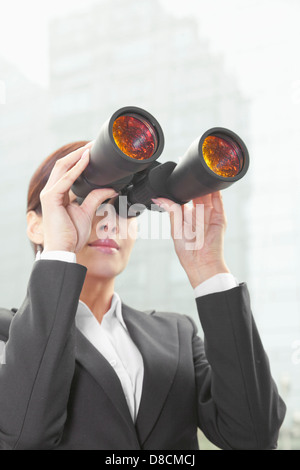 Geschäftsfrau, die mit dem Fernglas außerhalb in Peking Stockfoto