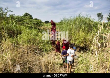 25. Mai 2013 - Mae Sot, Tak, Thailand - eine burmesische Mönch führt Neulinge durch den Wald während ihrer Morgen Almosen Runden durch eine inoffizielle Dorf der birmanischen Flüchtlinge nördlich von Mae Sot, Thailand. Ihre Gemeinde ist etwa 50 Meter von der burmesischen Grenze zu Thailand. Etwa 200 Menschen leben in strohgedeckten Hütten in der gesamten Gemeinschaft zu verbreiten. Sie sind nah genug, um Mae Sot, die einige können in der Stadt arbeiten und birmanische Händler von Mae Sot kommen, um ihr Dorf, um mit ihnen Geschäfte machen. Die Birmanen im Dorf nicht Residency Papiere für Thailand und gelten als technisch illegale Zuwanderung Stockfoto