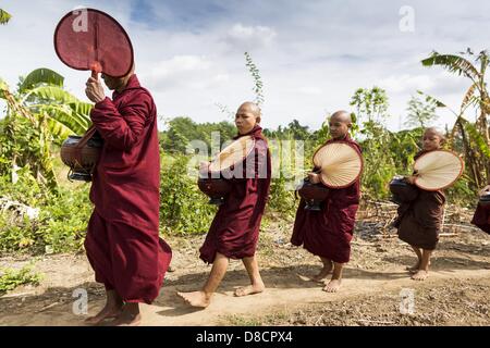 25. Mai 2013 - Mae Sot, Tak, Thailand - eine burmesische Mönch führt Neulinge durch den Wald während ihrer Morgen Almosen Runden durch eine inoffizielle Dorf der birmanischen Flüchtlinge nördlich von Mae Sot, Thailand. Ihre Gemeinde ist etwa 50 Meter von der burmesischen Grenze zu Thailand. Etwa 200 Menschen leben in strohgedeckten Hütten in der gesamten Gemeinschaft zu verbreiten. Sie sind nah genug, um Mae Sot, die einige können in der Stadt arbeiten und birmanische Händler von Mae Sot kommen, um ihr Dorf, um mit ihnen Geschäfte machen. Die Birmanen im Dorf nicht Residency Papiere für Thailand und gelten als technisch illegale Zuwanderung Stockfoto