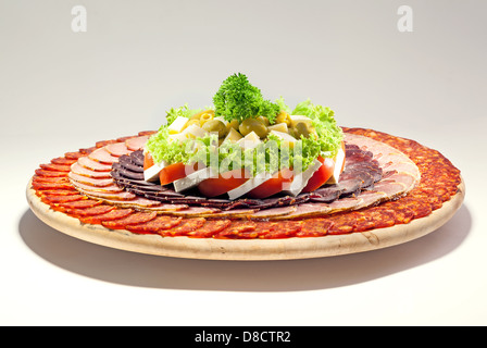 Salat und verschiedene Fleischstücke dekoriert und auf große Holzplatte. Stockfoto