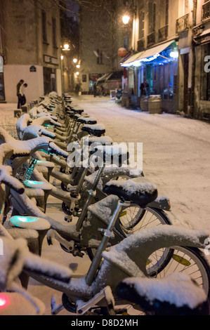 schneebedeckte Fahrräder in Paris Velib-Station. Stockfoto
